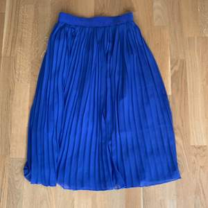 Mellanblå plisserad kjol. Resår i midjan. 73cm lång. 