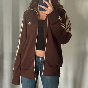 Brun adidas tröja  - Så snygg zip up hoodie från adidas. Jättefin brun färg med beiga detaljer, storlek XL men sitter fint oversized på mig som brukar ha S. Så bekväm och passar så bra som en tjockare tröja på sommarkvällar! Jättefint skick! Om fler är intresserade så blir det budgivning 🤎🤎 högsta bud 300!
