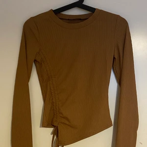 Ribbad topp - En ribbad topp med ett snyggt snöre och fina detaljer. Den är i storlek S. Den är i nyskick (ej använd) då jag råkat beställa 2 likadana tröjor. 
