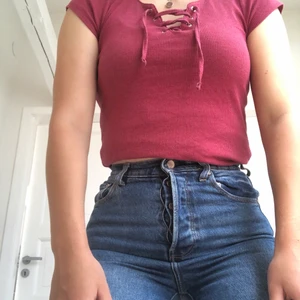 En röd topp med knutna detaljer. S/36 - En röd T-shirt. Den sitter rätt tajt som gör den perfekt att användas som en crop topp. I storlek S/36.