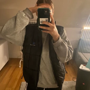 Svart väst - Säljer min unisex svarta vintage väst, inga fel (smutsig spegel), fickor med dragkejda både utanpå och även en innanför. Går att dra åt längst ner ifall att man vill den ska sitta lite tajtare. Väldigt go och varm, bra nu till hösten🍂 Köp eller Buda gärna: från 200kr + frakt. Köp direkt för 280kr + frakt☺️