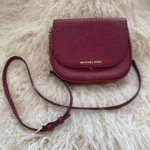 Michael Kors Axelremsväska  - Axelremsväska mindre , slitning vid skinnet vid knapp inget som syns när den är stängd. (Se bilder) Röd. 13X17 CM