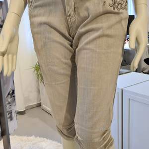 Stretching byxor i jeansmodell med fickor och hällor runt om. Detaljrika med sydda mönster och matchande stenar. Stentvättade i beige ton. Rynk veck sydda på sidorna av besluten. Slim fit  stl. 36