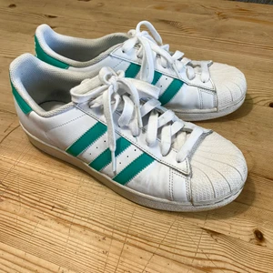 Adidas Superstar sneakers strl 42 - Fräscha Adidas sneakers i vitt och turkos. Bra skick overall då de knappt har använts. Storlek 42