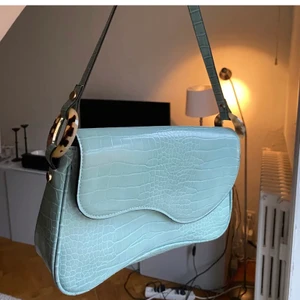 Ljusblå axelväska - Kort ljusblå axelväska med ”krokodilmönster”, köpt för 250 från topshop i london början av förra året, skitsnygg men får inte användning för den❤️ (lägger upp igen)