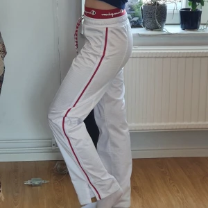Champion track pants - Supersnygga träning/mysbyxor från Champion! De har ett rött band längst midjan med Champion märket och slitsar vid anklarna. Funkar både som hög och lågmidjade! Tunt tyg. Jag är 160cm, köparen står för frakt annars mötas i Stockholm💗 