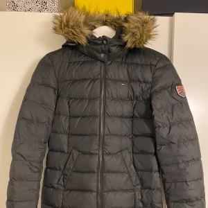 Tommy Hilfiger jacka - Varm täckjacka ifrån Tommy Hilfiger. Mycket sparsamt använd. Vadderad. Avtagbar huva, samt avtagbar pälskrage på huvan. Storlek XS.
