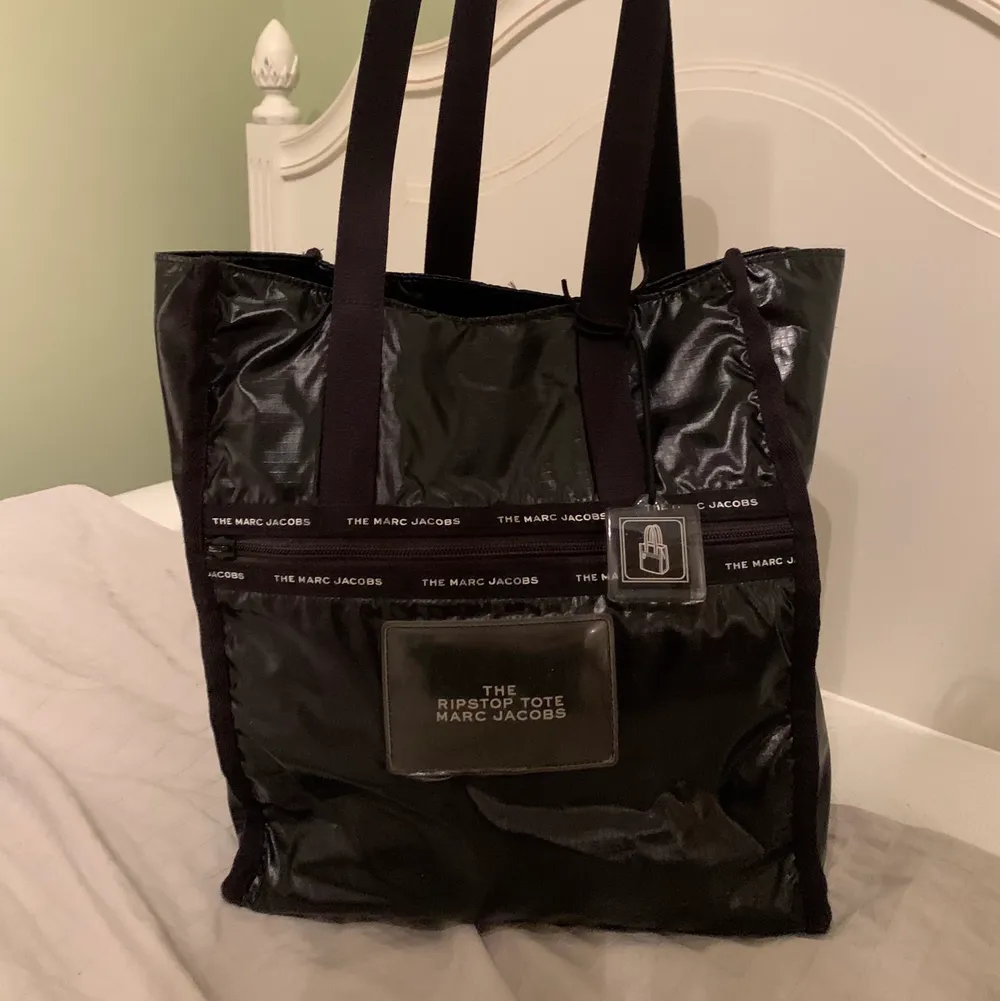 Säljer min supersnygga svarta väska från Marc Jacobs i modellen ”ripstop tote”. Den är rymlig och praktisk och har ett stort innerfack. Perfekt som en vardagsväska eller träningsväska då väskan även är mycket lätt. I gott skick men har tappat ett ”handtag” till dragkedjan (syns på sista bilden) men dragkedjan funkar fint ändå! Nypris 2000kr. Väskor.