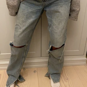 Blåa jeans med slits - Supersnygga jeans med hål vid knäna samt slits. Jeansen lägger sig fint över skor och kan bäras på höfterna. Passar någon runt 160- 170 cm. Bra skick! 