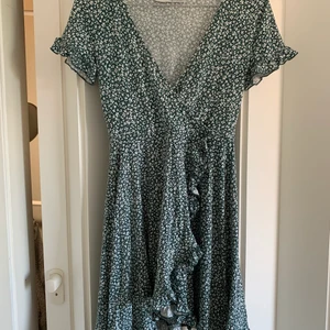 Grön miniklänning med blommigt mönster - Jättesöt grön miniklänning med blommigt mönster och volanger ifrån pull & bear, Stretchigt material i storlek xs