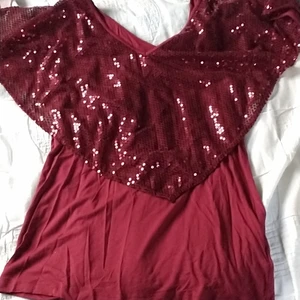 Vinröd tröja med paljetter - En vinröd V-ringad tröja från tidigt 2000-tal med paljetter i st XL. Från Rainbow. Skriv för fler bilder.