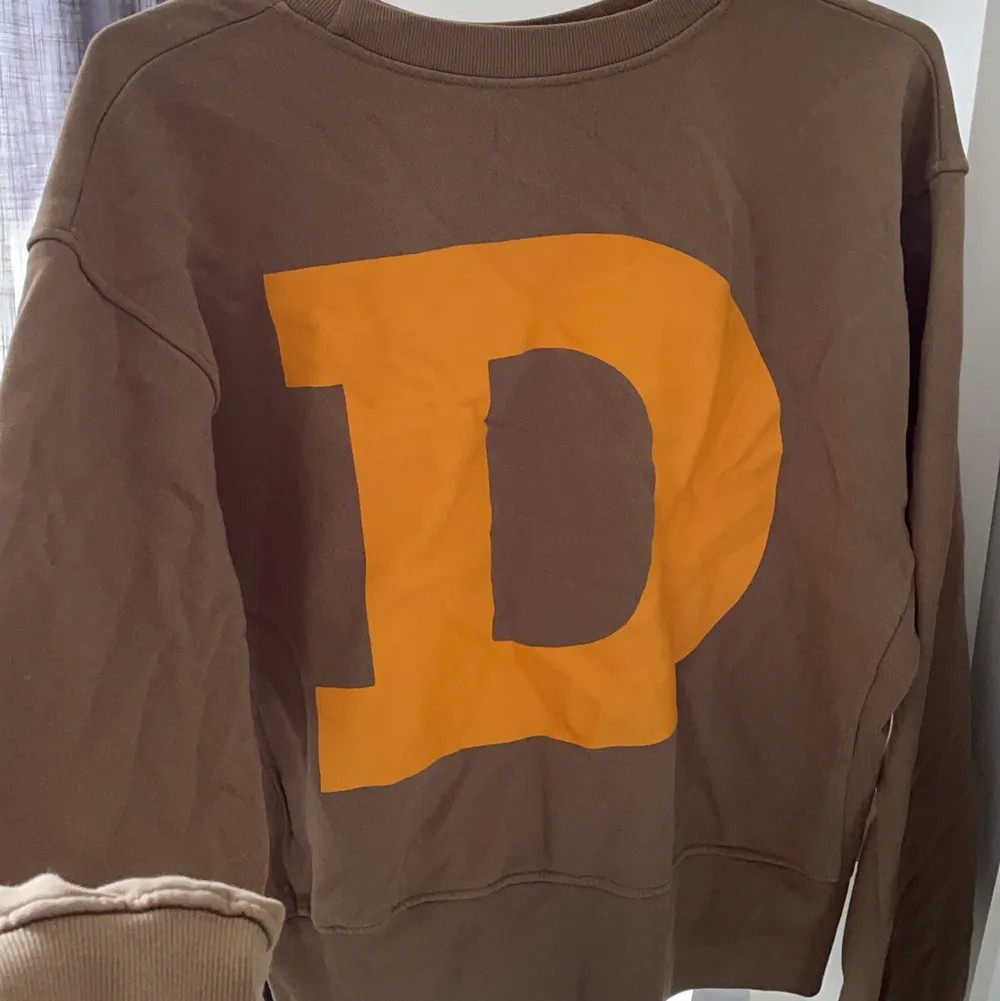 Brun sweatshirt med ett orange D på ryggen som en häftig detalj. Helt oanvänd😊. Tröjor & Koftor.