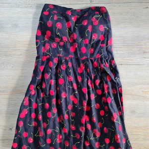 Körsbärsklänning - Strapless körsbärsklänning med stretch I ryggen. Klänningen knyts med en rosett I ryggen. 