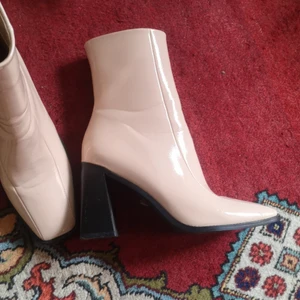 Skor med fyrkantig tå och blockklack  - Ankellånga stövletter i ljusrosa patent-material. Passar storlek 38. Jättesnygga men tyvärr bara använt en gång och sen legat i garderoben. (Kan även skicka men vet ej hur mycket frakten blir)