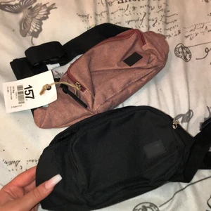 Två magväskor/axelväskor från lager 157 - Den rosa är helt oanvänd, prislapp kvar. Den svarta är använd ungefär 2 gånger. Det finns 3 olika fack, ett litet på baksidan av väskan som jag använt för mina kort och sedan ett stort fack och ett lite mindre . Justerbart band. Kan mötas upp i Stockholms området, annars står frakten för köparen. 