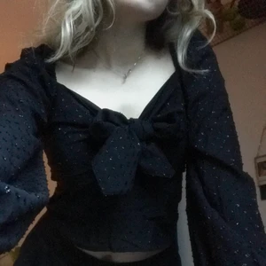 Knyt-blus 🌹 - Använd en gång🌟 croppad, och under rosetten (som man knyter själv) är det en liten cut-out. Ballongärm och glittriga prickar. 