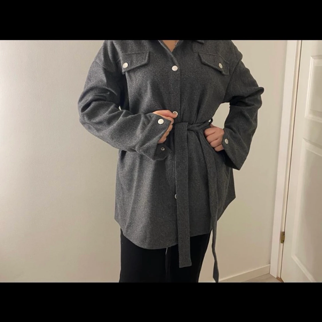 Mörkgrå kappa med band. 