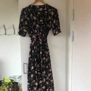 Blommig lång omlottklänning - Klänning från bikbok i nyskick! Storlek L men sitter bra på mig som brukar ha M. Pris är förhandlingsbart :) 