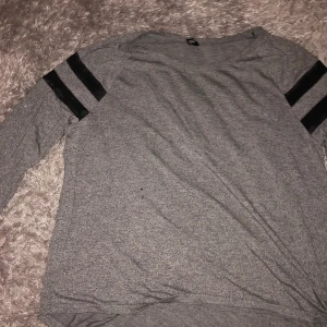 Grå tröja  - Helt vanlig grå tröja i lite spräckligt grå färg och ställen på armarna är i ”nät”