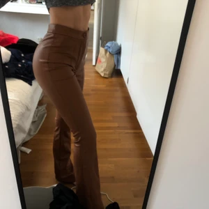 Skinnbyxor  - Bruna utsvängda skinnbyxor från NAKD. Storlek 32 men passar en storlek 34 lika bra!! Köpare står för frakten.