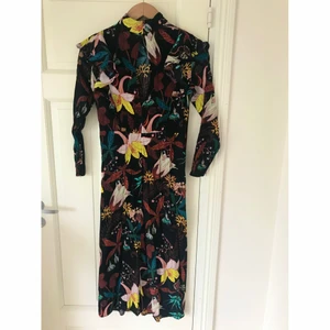 Fantastisk blommig sommar vår klänning strl 36 - Blommig klänning i strl 36 med härligt mönster och knäppning i ryggen, sitter kanska figurnära men inte jättetight på någon som typiskt bär strl 36. Längden går till mellan vaden och ankeln på mig som är 169cm. Passar både till vardags och till fest. Obs klänningen är ej struken på bilden.