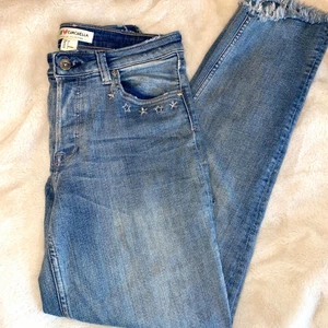 Slitna jeans med stjärnor  - Säljer mina ljusblåa croppade jeans med slitningar och stjärnor då de inte passar längre. Strl 34 men väldigt stretchiga så passar även 36. (Jag hade 36 men kunde ha dessa). En söm har gått upp där bak men enkelt att sy ihop. Fraktar endast och köparen står för frakten. 🤍