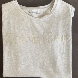 Calvin Klein t-shirt! - säljer denna snygga gråa, det är svårt att de färgen på trycket men det är iaf silver. kontakta mig privat om fler bilder önskas! frakt tillkommer & priset kan diskuteras.