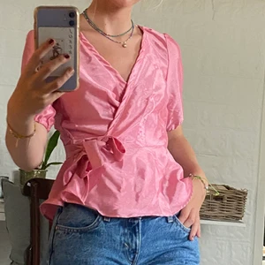 Rosa blus med knyte från Vero Moda - Säljer denna för att jag inte fyller ut den riktigt! Annars extremt fin nyans av rosa och pyttelite glansig! Använd EN gång förra året på fest! Misstänker att det blivit fabriksfel när dom tillverkade denna för lappen är typ ”insydd” i nacken, dessutom verkar stygnen lite konstiga men detta syns INTE när man har på sig den! 