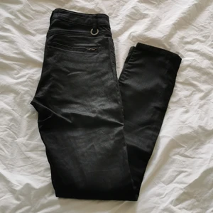 Jeans fr STOCKH LM - Svarta, glansiga och smala stuprörsjeans med snygga dragkedjedetaljer. Storlek 34, känns som vanlig small. Mjuka och stretchiga. Använda ett fåtal gånger. Nypris 799kr