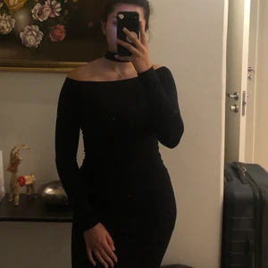 Svart långärmad tajt klänning - Svart tajt halvt off-shoulder klänning i jätteskönt material. Formar kroppen jättefint och har en inbyggd choker 