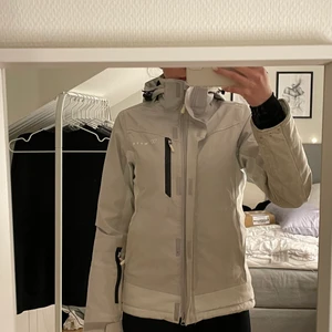 Skidjacka - Vit/grå skidjacka i stl xs som endast använts en skidsäsong. Den har både ute- och innefickor och även snölås. Jackan fungerar även bra som vanlig vinterjacka då den är varm och skön. Säljes då den blivit för liten för mig. ( Eventuella fraktkostnader ingår ej i priset.)