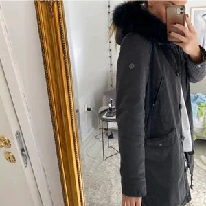 Pälsjacka - Svart/grå vinterjacka. Köpt för cirka 8000kr org. Storlek 38. Använd 1 vinter, men använd väldigt flitigt. Finns lite små”fel”, en fläck på ärmen, och i jackan. Även ett litet hack som på bilden. Skickar gärna mer bilder. Äkta päls. Kan mötas i gbg, annars fraktas gentemot kostnad. Pris kan diskuteras