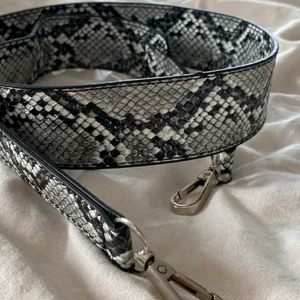 Väskband  - Väskband i ormmönster. Aldrig använd. Från Nelly.com. I nysick. Fauxlether. 🐍 ca 4 cm bred. 