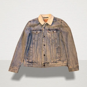 Levi’s fodrad jeansjacka - Neutrala färger Löst snitt Knappband Bröstficka Sidofickor Jeans Lättfodrad Tvätteffekt Teddyfoder Label Patch/Label Flag Ytmaterial: 100% Bomull Konstgjord pälsbräm: 100% Polyester Ärm: 100% Polyester Ärmfoder: 100% Nylon. 