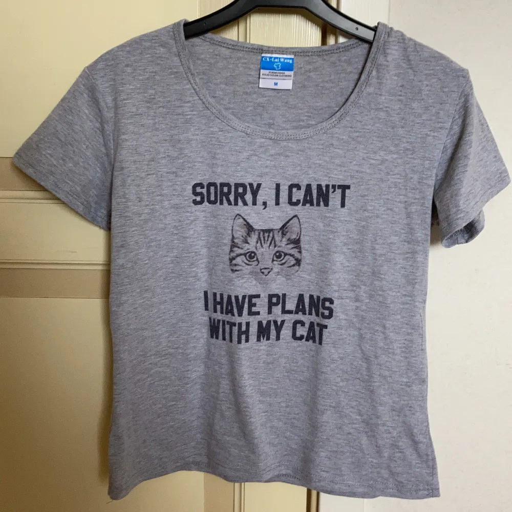 Grå T-shirt med trycket ”Sorry I Can’t I have plans with my cat”. Strl M men väldigt liten i storlek så passar XS/S.. T-shirts.