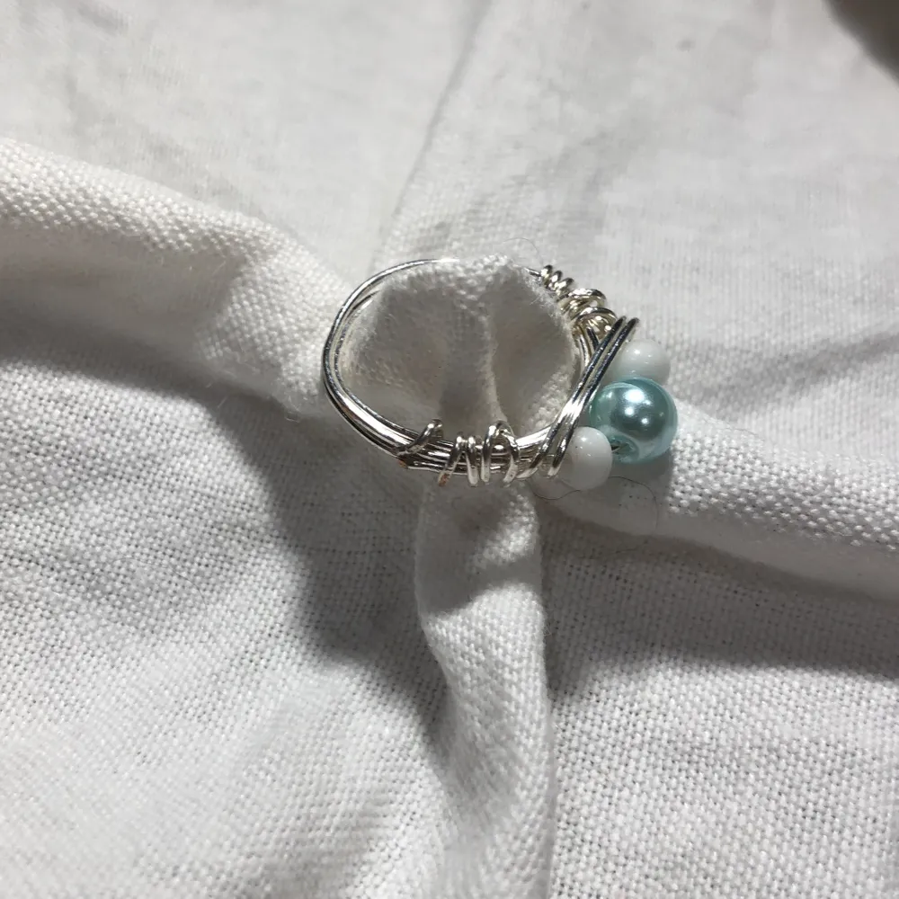 En hemmagjord ring med två små vita pärlor och en stor ljusblå pärla. Passar bra till mycket. 70kr med frakt!🚚. Accessoarer.