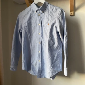 Ralph Lauren  - Säljer en ljusblå skjorta från Ralph Lauren som endast är testad och inte kommer till användning. Det är storlek 16 ”costum fit”, skulle säga att den passar 165 cm. 