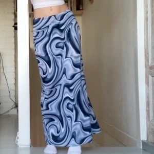 Långkjol funky mönster - Lång silky kjol med jättefina blå färger och världens coolaste mönster, uppenbarligen från 00’s och har helt klart y2k känsla. kan bäras låg- och högmidjat efter smak och passar alla från S - L pga stretch i midjan! skriv till mig vid frågor❤️ fler bilder kan skickas vid behov!!💗💕💗💕💗💕 PS: om någon är intresserad av att köpa direkt kan vi diskutera pris i chatten