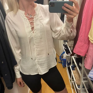 Blus  - Säljer denna fina blus med snörning som detalj i fram och känns som den är gjord i satin liknade material. Köpt för några år sedan men använd två gånger. Storlek XS men skulle säga att det är en mer som en S 