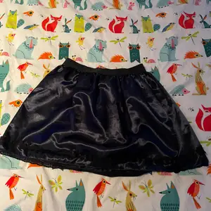 Säljer en kort kjol i glansigt marinblått tyg med spets längst ner, den är så cool men kommer tyvärr inte till användning