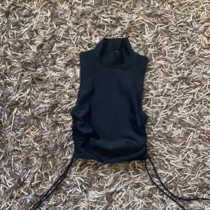 Svart topp med dragsko  - Säljer en svart topp med dragsko. Exakt likadan som den bruna topp som jag också säljer. Denna är aldrig använd. Kan mötas i Göteborg eller Karlskrona annars står köparen för frakten.