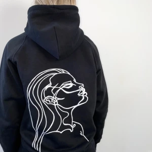 Svart hoodie  - En miljövänlig hoodie i svart. Våra produkter på Fewear UF uppmärksammar "våld mot kvinnor i nära relationer". Hoodisarna är tillverkade av ekologisk bomull och är fairtrade-märkta. 10% av vår vinst går till Kvinnojouren i Umeå 💗 OBS: Finns nu endast kvar i S och L! 