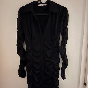 Svart klänning - Svart kort klänning från NA-KD köpt i somras. Använd 1 gång. Genomskinliga armar,  figursydd och väldigt stretchig. Heter gathered mesh mini party dress på hemsidan. Köpte klänningen för 400kr på hemsidan.