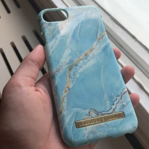 Ett blått skal till iPhone 8 - Ett jätte fint skal från ideal of sweden. Skalet är i en blå fin färg som ska likna marmor skalet har även magnet i sig. Skalet är i bra skick förutom att det är sönder i ett av hörnen. Jag säljer skalet för att jag inte tycker om det längre. Kontakta mig om det är något!