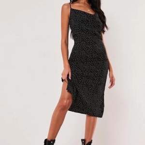 A midi dress featuring a all over polka dot print with adjustable straps and cowl neckline. Ej envänd, nypris 300kr