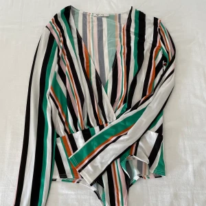 Body från Nelly - En färgglad body som ger en känsla av 80-talet. Sitter bedårande när man har på sig den. Pris 120kr. Finns k Kalmar eller Halmstad annars står köparen för frakt. 