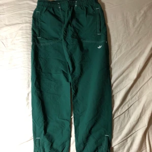 Adidas Trackpants - Mörkgröna trackpants från Adidas. Storlek M och bara använda ett fåtal gånger. Ankellängd på mig som är ca 173. Byxorna har dragkedjor längst ner på benen för att göra benöppningnen en aning större. Dom har både resår och snören i midjan. så dom passar nästan alla. Kan mötas upp på Södermalm, helst vid Skanstull. Annars betalar köparen för frakten.