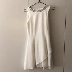 En super fin vit klänning som är helt oanvänd! Klänningen har en snedskuren look från vänster sida som är täckt i ett annat material en själva klänningen. Inköptes Australien