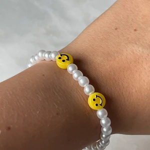 Double happines  - Jätte fint trendigt armband med stora vita pärlor och med två smileys. Ingår spänne och ringödlor så man kan justera det efter önskan.