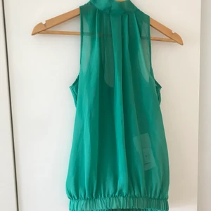 NY sommartopp - Snygg elegant sommartopp i en jätte fin färg Smidig detalj längst ner för att hålla toppen på plats och hamnar under tröjan Halvöppen rygg med en fin knytningsdetalj på baksidan See through 🔥 Helt ny  Passar XS/ strkl 34  Kan skickas mot frakt, fraktpriset står i nästa steg 📦  Alla betalningar sker tryggt via Swish. 🤝  Inga returer, plagget säljs i befintlig skick enligt bild och beskrivning. ❌